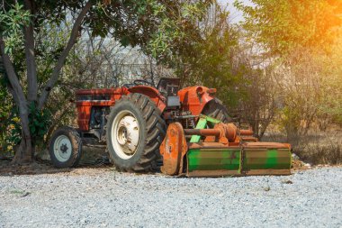 Köydeki ağaçların ve çalıların yanında saban süren eski bir traktör var.