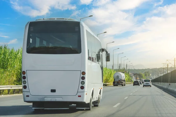 White modern comfortable tourist bus driving through highway at bright sunny day. Travel and coach tourism concept. Trip and journey by vehicle