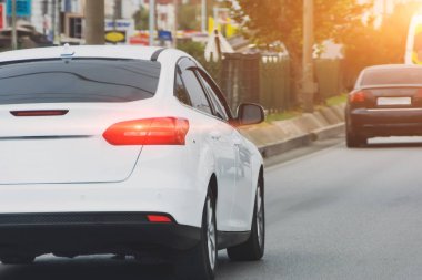 Beyaz araba, şehir yolunda başka bir karanlık arabayı takip ediyor.