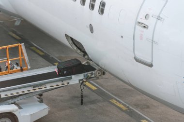 Bagajları uçağa yüklüyorum. Uçaktan uçağa taşıyıcı banttaki bavullar