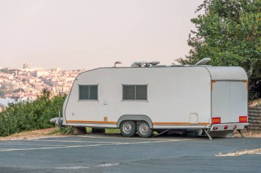 Şehir merkezinden dağ tepe manzaralı cadde parkına park etmiş tekerlekli bir minibüsün üzerindeki mobil ev karavanı..