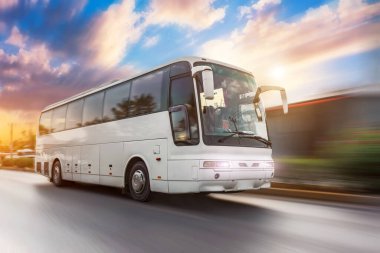 Bus driving moving at high motion blur effect speed on a road in the sunset clipart