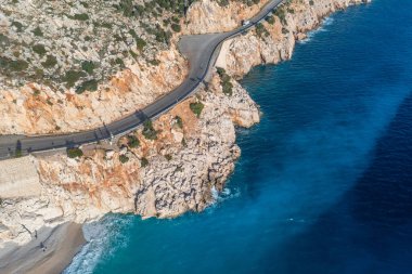 Dağ yılanının üzerindeki bir dronun görüntüsü. Dağ yolunda giden araçların hava görüntüsü. Akdeniz kıyısındaki tatil köyü plajı.