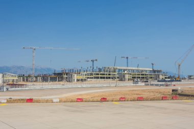 Yeni bir havaalanı terminali inşaatı, etrafta park edilmiş vinç ve uçak manzarası. Taşıma merkezi yeniden yapılandırması