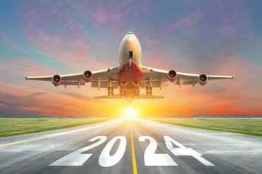 Havaalanı yolunun 2024 numaralı pistinde büyük bir uçağın kalkışıyla gün batımının tadını çıkarın. Yeni yılda seyahat kavramı, tatiller