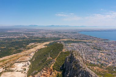 Tepe dağları üzerinden uçuş çalılarla kayalık arazi, şehre bakan kuş bakışı manzara, evler ve binalar, yollar ve gemiler, Akdeniz kıyıları, tatil bölgesi, tatil gezisi
