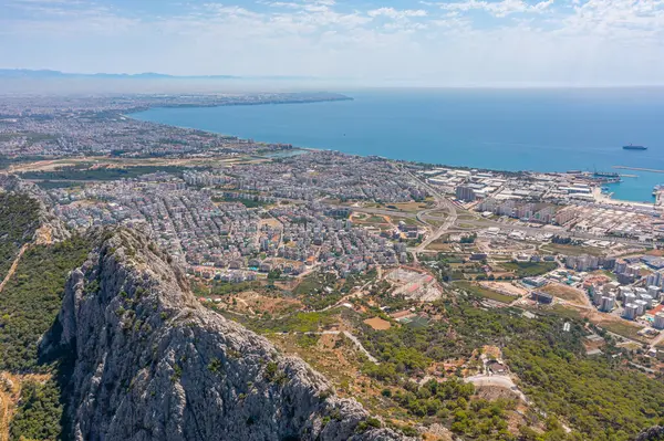 Tepe dağları üzerinden uçuş çalılarla kayalık arazi, şehre bakan kuş bakışı manzara, evler ve binalar, yollar ve gemiler, Akdeniz kıyıları, tatil bölgesi, tatil gezisi