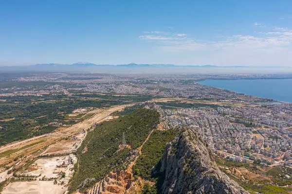 Tepe dağları üzerinden uçuş çalılarla kayalık arazi, şehre bakan kuş bakışı manzara, evler ve binalar, yollar ve gemiler, Akdeniz kıyıları, tatil bölgesi, tatil gezisi