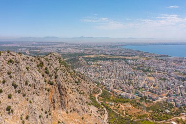 Tepe dağları üzerinden uçuş çalılarla kayalık arazi, şehre bakan kuş bakışı manzara, evler ve binalar, yollar ve gemiler, Akdeniz kıyıları, tatil bölgesi, tatil gezisi