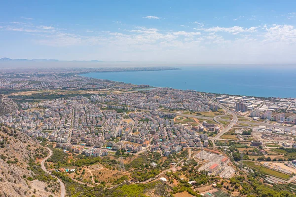 Tepe dağları üzerinden uçuş çalılarla kayalık arazi, şehre bakan kuş bakışı manzara, evler ve binalar, yollar ve gemiler, Akdeniz kıyıları, tatil bölgesi, tatil gezisi