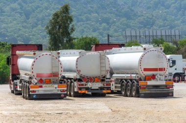 Bir deponun önünde yakıt tankları olan kamyonlar ve ana otoyolun yanındaki büyük hammadde konteynırlarının depolanması..