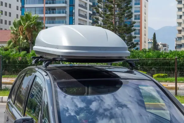 Black plastic car rooftop cargo box or roof carrier for traveling. Removable storage container mounted on car roof rack.