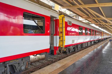 Yolcu vagonları tren istasyonunun platformunda beyaz kırmızı renkte.