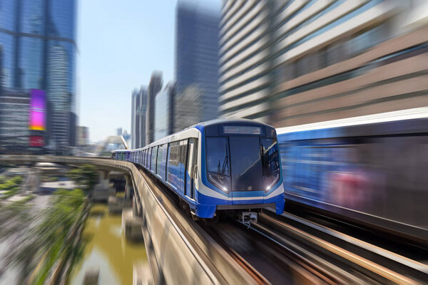 Modern high speed train over ground on a bridge on stilts among skyscrapers metro with turn speed motion blur