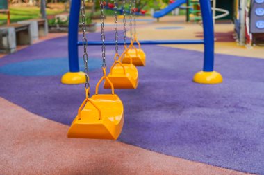 Bir apartmanın avlusundaki çocuk parkında sarı mavi renk salla.