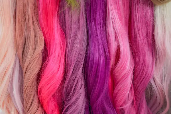 Hair samples of different colors palette. Different hair bright rich tint colors - pink, crimson, orange. Various hair colors set background close up view. Extension equipment of natural