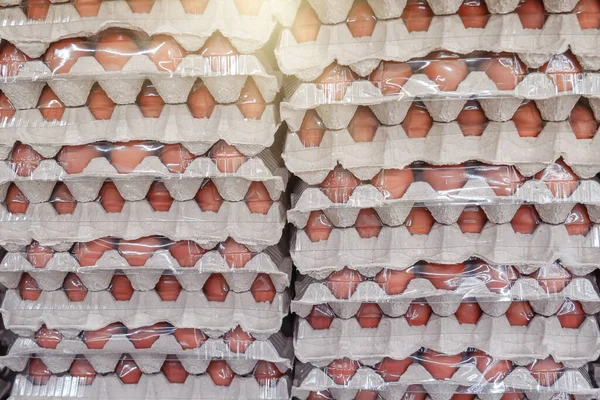 Many stacks of rows and paper packaging plastic cling film for chicken eggs, stacked in a store, brought from poultry farms in rural areas for sale in city stores.