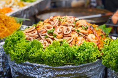 Sokak tezgahında taze yeşil salata içinde ahtapot ve mürekkep balığı dokunaçları