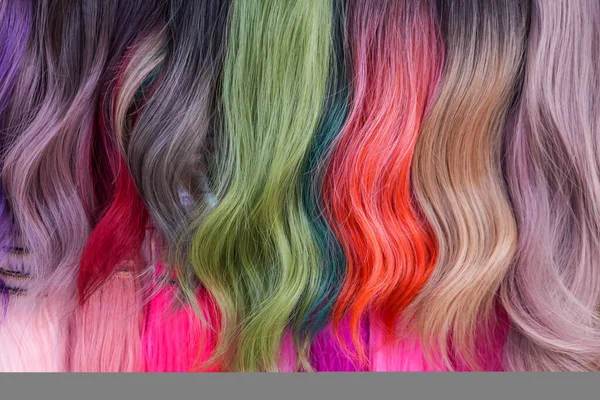 Hair samples of different colors palette. Different hair bright rich tint colors - pink, green, crimson, orange. Various hair colors set background close up view. Extension equipment of natural