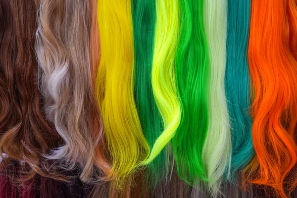 Hair samples of different colors palette. Different hair bright rich tint colors - yellow, green, crimson, orange. Various hair colors set background close up view. Extension equipment of natural