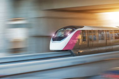 Parlak farları olan modern yüksek hızlı tek raylı tren, akşamüstü tüneldeki viyadük tünelinden geçen yarış istasyonundan geçer.