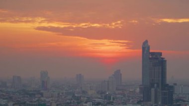 İş bölgesindeki modern ofis binaları üzerinde günbatımını hızlandırıyor. Disk güneş ışığı ve parlaklığıyla şehrin ufuk çizgisi manzarası