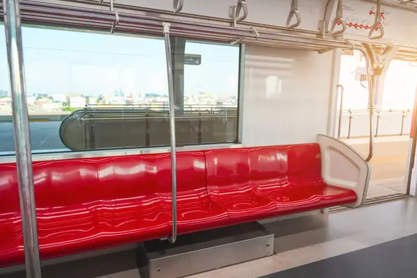Interior of a passenger car of a commuter train. Red plastic seats and chrome handrails inside an electric train carriage car.