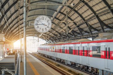 Tren istasyonundaki yolcu platformundaki bir direğin üzerindeki saat banliyö treninin gelişini bekliyor.