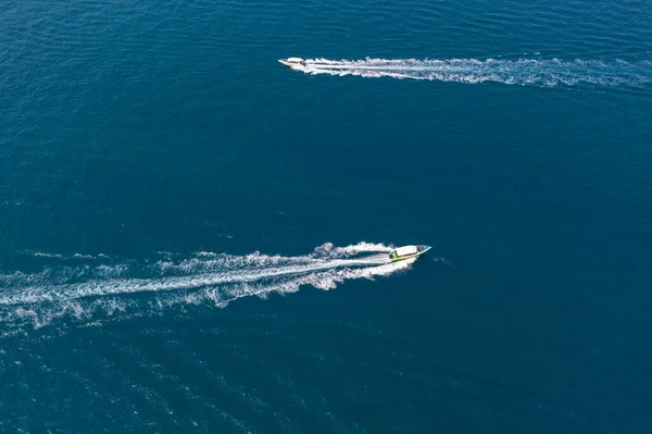 Two traffic flow of speedboats in the strait between tropical exotic islands, boats ply intensively carrying tourists. View from above top aerial.
