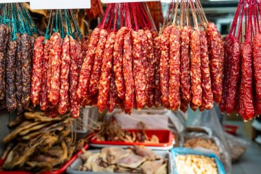 Kurutulmuş sosis diğer et ve balık ürünleriyle birlikte bir marketin vitrininde asılı duruyor.