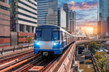 Elektrikli tren, parlak hafif tren vagonları günbatımı gökyüzü tren yolu viyayolu boyunca modern binalar, gökdelenler ve metropoller arasında yol alır..