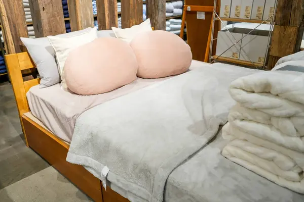 Double beds with glazed linens, duvet, sheets and pillows in furniture store.