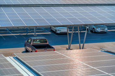 Güneş panelleri, park yerinin üzerine park edilmiş arabalarla dolu, temiz enerjinin etkin bir şekilde üretilmesi için paraşüt çatısı sığınağı ve hava manzarası..