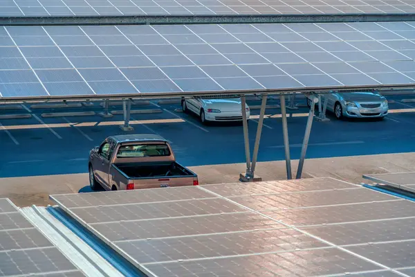 Solar panels canopy roof shelter installed over parking lot with parked cars for effective generation of clean energy, aerial top view.
