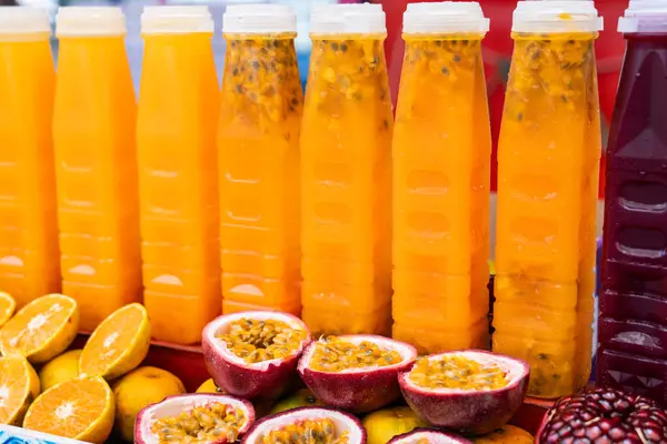 Freshly squeezed passion fruit and pomegranate juice in bottles for sale on the counter