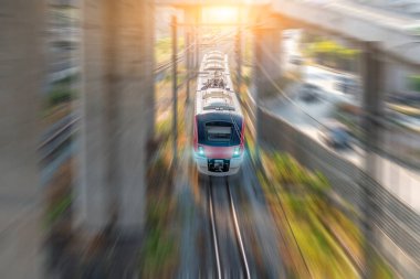 Parlak farları olan modern yüksek hızlı banliyö treni bir yol kavşağındaki tünelden geçerek sahnedeki yarış istasyonunu geçiyor..