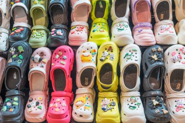 Timsahlar, pembe parmak arası terlikler, aksesuarlar ve mağaza penceresinde zincirler. Tayland, Phuket 24 Şubat 2024.