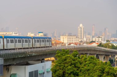 Elektrikli tren vagonu gökyüzü demiryolu yolu yolu boyunca hızla ilerliyor. Modern şehir binalar, gökdelenler, ağaçlar arasında bir metropol parkı..