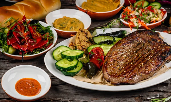 Bir sürü yiyeceği temsil eden çeşitli yiyeceklerle dolu bir ziyafet. Fırında ekmek, ızgara et, güzel karanlık bir masada çeşitli soslar. Üst Görünüm.
