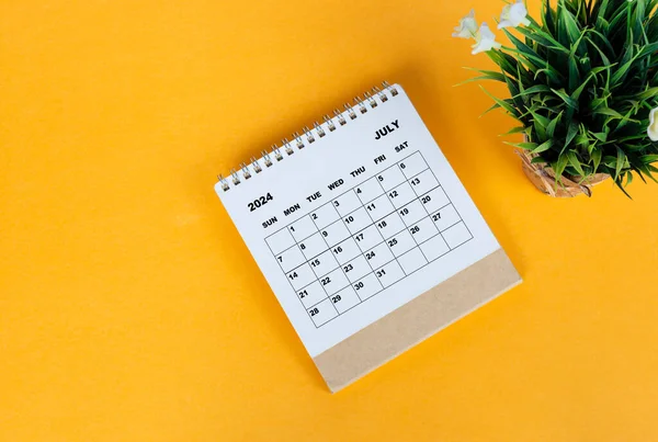 stock image July 2024 desk calendar on yellow background. Directly above. Flat lay. Copy space.