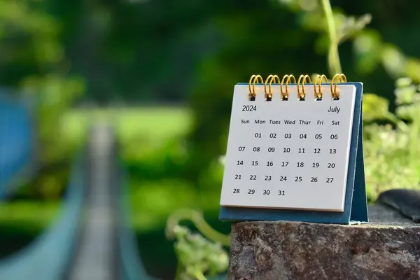 stock image July 2024 calendar with green blurred background of hanging bridge. New year concept.