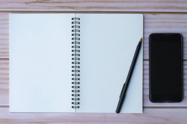 Kalem, not defteri ve akıllı telefonlu ofis masasının tam üstünde. Düz yatıyordu. Boşluğu kopyala.