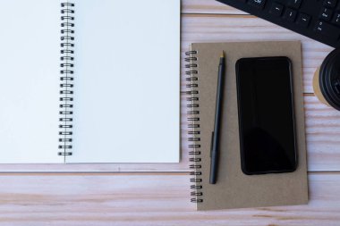 Kalem, not defteri, akıllı telefon, bilgisayar klavyesi ve kahveli ofis masasının tam üstünde. Düz yatıyordu. Boşluğu kopyala.