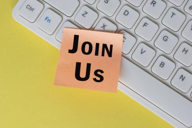 Beyaz klavyenin üstündeki turuncu notada bize katılın. İş konsepti.