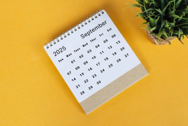 Eylül 2025 sarı arka planda masa takvimi. Tam üstte. Düz yatıyordu. Boşluğu kopyala.