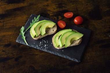 Siyah taşlı arka planda, baharatlı ve kirazlı avokadolu sandviçler. Üst Manzara. Mesaj için yer var. Yüksek kalite fotoğraf