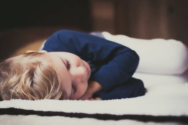 Close-up of cute kid sleeping on the bed. 