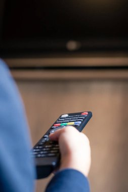 Close up of kid changing channels on television with remote control.