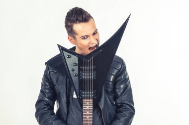 Portrait of musician biting his electric guitar and looking at camera.