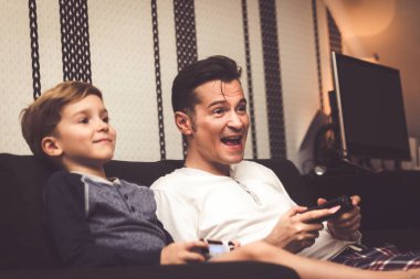Excited father playing video games with his son and having fun at home. 